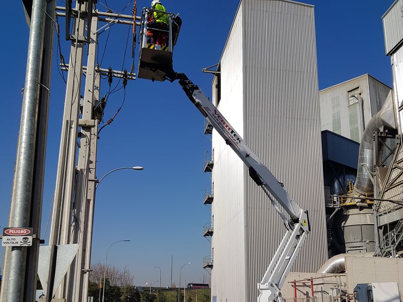 Trabajo en altura con plataforma elevadora junto a poste de distribución
